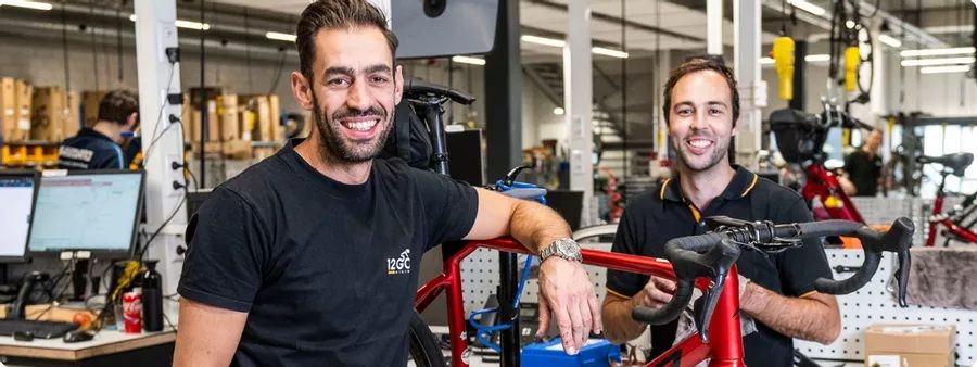 fietsmonteurs aan het werk met een rode racefiets