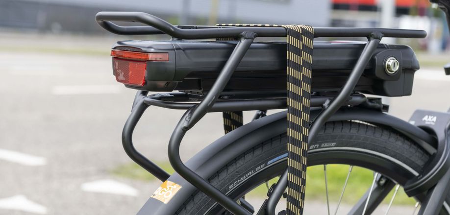Accu in bagagedrager van een e-bike met geel zwarte snelbinders en een 12GO Biking sticker op het spatbord