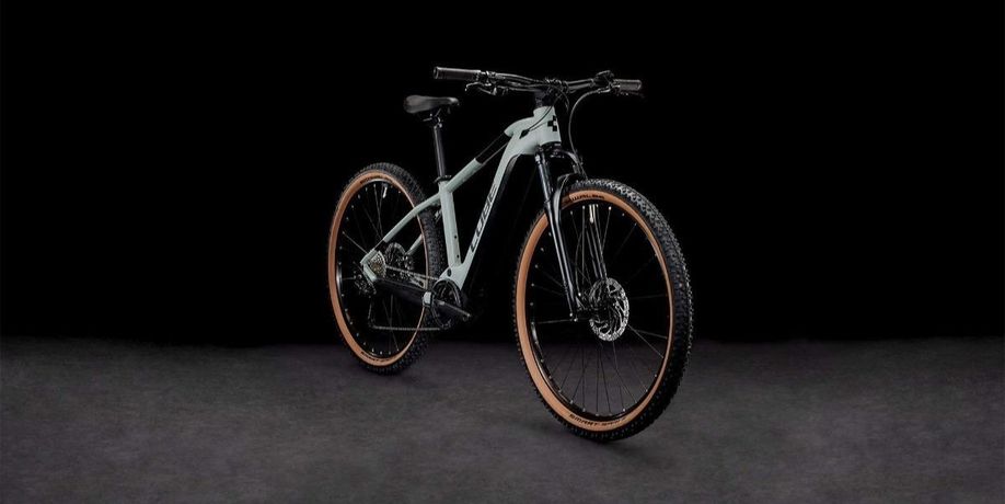 Schuin vooraanzicht van de Cube Reaction Hybrid Performance mountainbike in grijs met een zwarte achtergrond