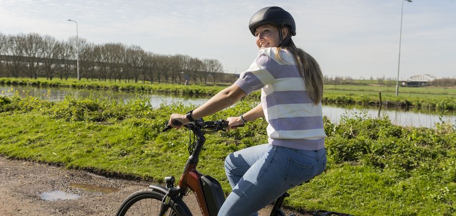 vrouw fietsend op e-bike met fietshelm op
