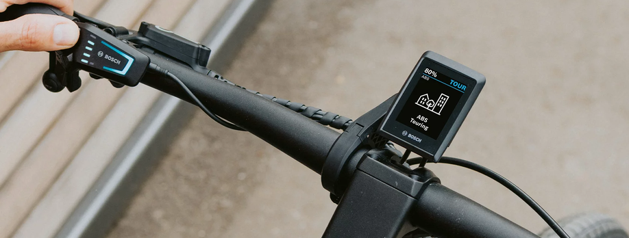 Bosch Kiox 500 display op een zwarte fiets met een persoon die de LED Remote met zijn duim bediend