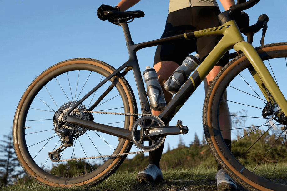 Man houdt zwartgroene Scott gravelbike met Shimano GRX820 onderdelen vast op het gras