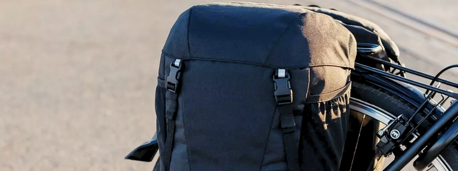 Zwarte dubbele fietstassen op een bagagedrager van een fiets met kliksysteem voor de bovenkant