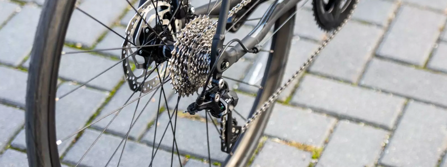 Achterderailleur en cassete van een zwarte racefiets op een weg van klinkers