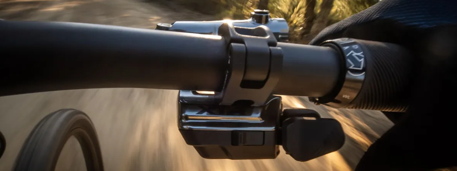 Close-up van de Shimano XTR shifter met een handschoen van iemand op het handvat ernaast terwijl die aan het fietsen is