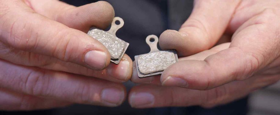 Twee remblokken in de handen van een persoon met zwarte vingers van het werken