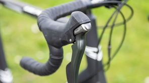 Mechanische shifter op een zwarte racefiets met veel kabels in het zicht voor groen gras