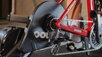 Close-up van een rode Trek met SRAM afmontage op een Wahoo Kickr fietstrainer met een tapijt en betonnen muren erachter