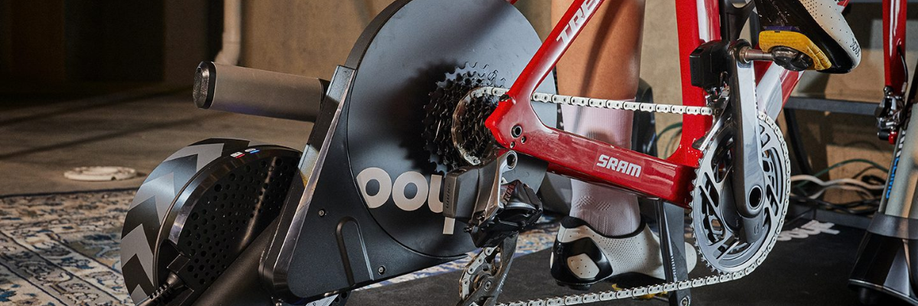 Close-up van een rode Trek met SRAM afmontage op een Wahoo Kickr fietstrainer met een tapijt en betonnen muren erachter