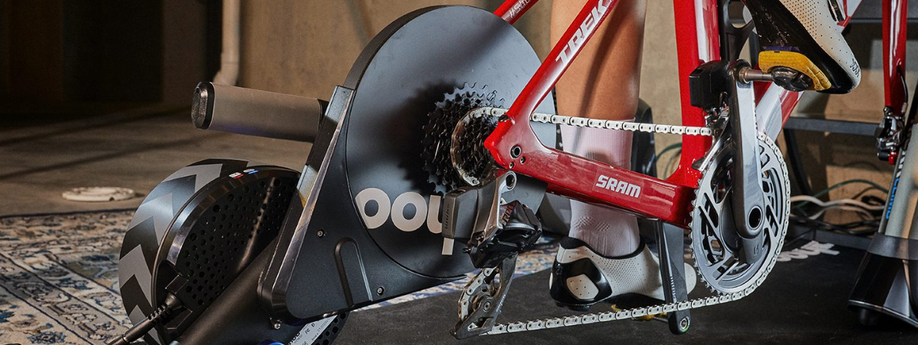 Close-up van een rode Trek met SRAM afmontage op een Wahoo Kickr fietstrainer met een tapijt en betonnen muren erachter