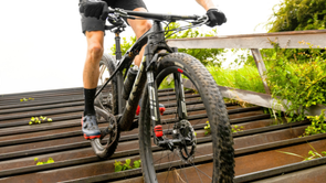 Mountainbiker staat op zijn pedalen en fietst van de trap af terwijl de voorvork voor demping zorgt