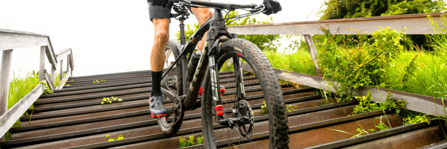 Mountainbiker staat op zijn pedalen en fietst van de trap af terwijl de voorvork voor demping zorgt