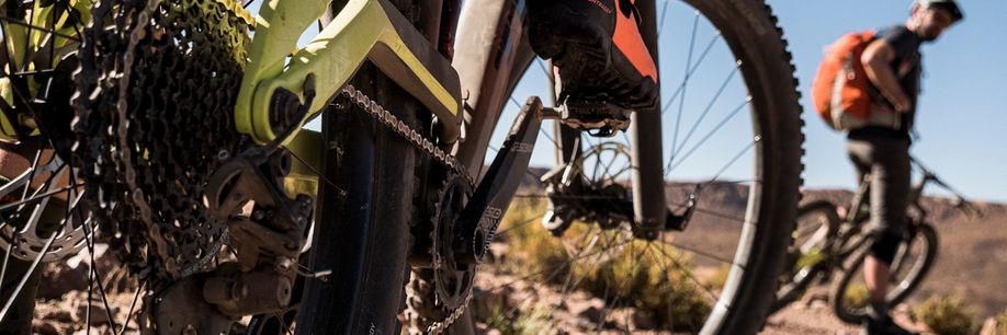 Versnellingsgroep op een groene mountainbike met andere mountainbiker die ervoor stilstaat met rode rugzak in de bergen