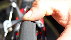 Duim van persoon duwt op de buitenband van een racefiets met velgremmen om te testen hoe hard de band is