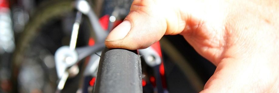 Duim van persoon duwt op de buitenband van een racefiets met velgremmen om te testen hoe hard de band is