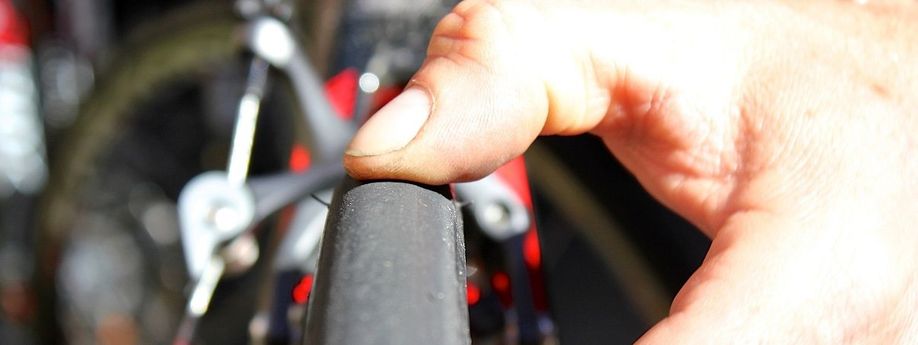 Duim van persoon duwt op de buitenband van een racefiets met velgremmen om te testen hoe hard de band is