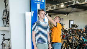 Medewerker van 12GO Biking meet lengte van een klant met behulp van een Shimano hoogtemeter in de showroom van 12GO Biking