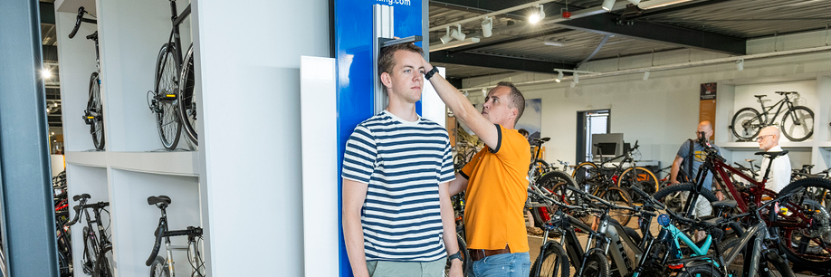 Medewerker van 12GO Biking meet lengte van een klant met behulp van een Shimano hoogtemeter in de showroom van 12GO Biking