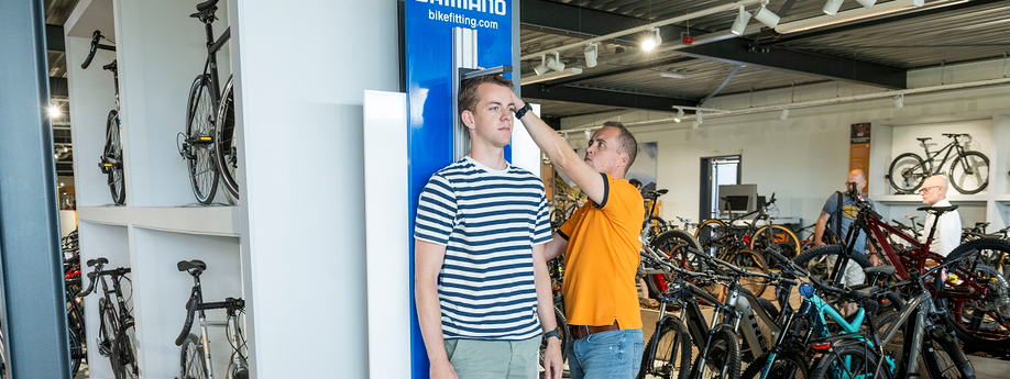 Medewerker van 12GO Biking meet lengte van een klant met behulp van een Shimano hoogtemeter in de showroom van 12GO Biking