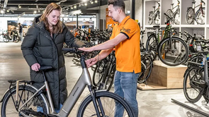 Verkoper praat tegen klant met grijze Batavus fiets in de showroom van 12GO Biking