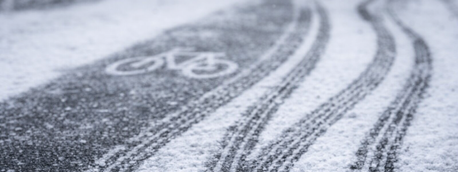 Bandensporen van fietsen op een asfaltweg met sneeuw