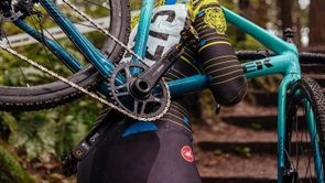 Man loopt met blauwgroene Trek cyclocrosser de trappen van een bos omhoog met aan de zijkant een wit lint met Trek logo's