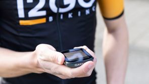 Garmin fietscomputer in hand van fietser met 12GO Biking fietsshirt