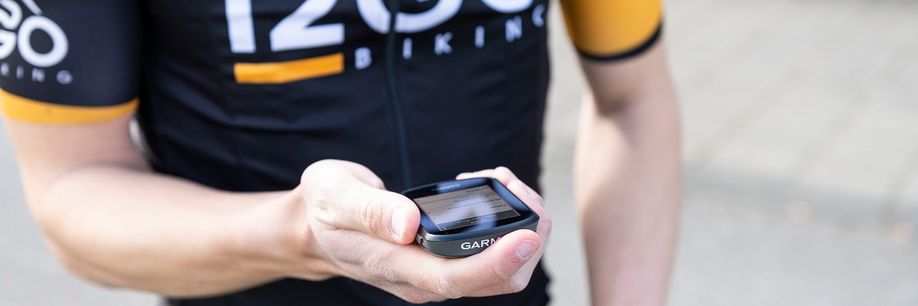 Garmin fietscomputer in hand van fietser met 12GO Biking fietsshirt