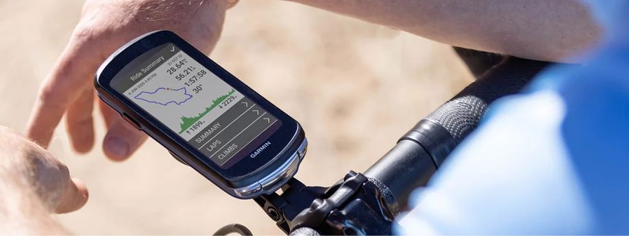 Garmin fietscomputer op stuur gemonteerd met persoon in blauw shirt die op het stuur hangt