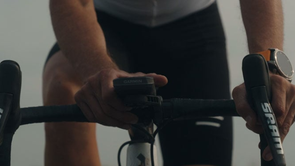 Garmin fietscomputer op een racefietsstuur met SRAM shifters en iemand die de knoppen van de fietscomputer bedient