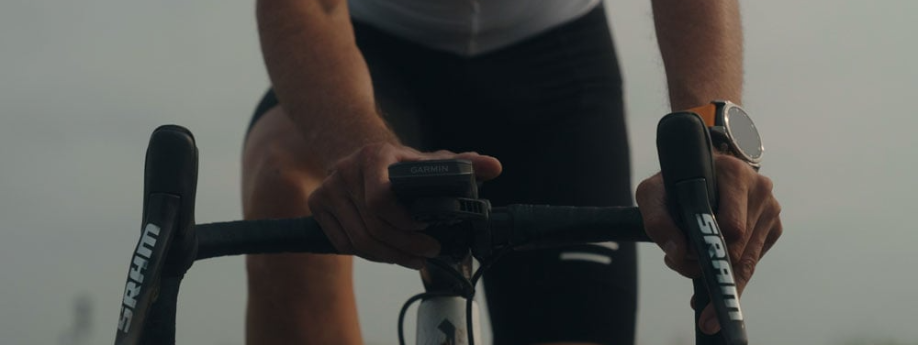 Garmin fietscomputer op een racefietsstuur met SRAM shifters en iemand die de knoppen van de fietscomputer bedient
