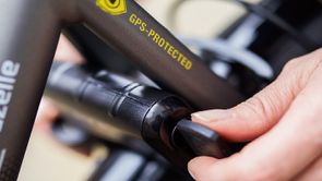 Fietser draait sleutel om van ringslot op een grijze Gazelle fiets die een GPS-Protected sticker heeft