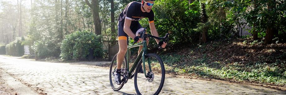 12GO wielrenner met groen racefiets over kasseien