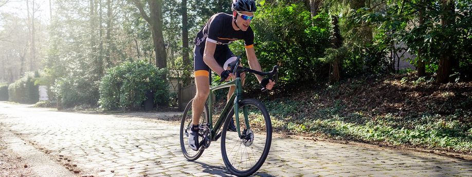 12GO wielrenner met groen racefiets over kasseien