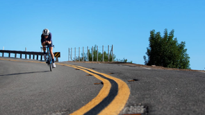 Triatleet op een Trek Speed Concept tijdritfiets die afdaalt over een asfaltweg met gele lijnen en een helderblauwe lucht