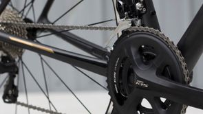 Shimano 105 groepset met voor- en achterderailleur op een zwarte racefiets voor een witte achtergrond