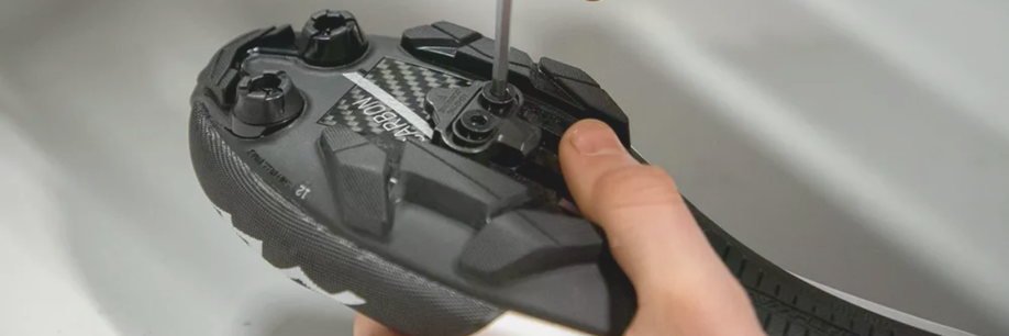 Vastdraaien van de bouten met inbus van een SPD-schoenplaatje onder een mountainbikeschoen