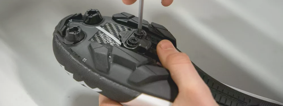 Vastdraaien van de bouten met inbus van een SPD-schoenplaatje onder een mountainbikeschoen