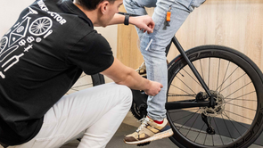 Persoon met Bike Doctor shirt met de hoek van de knie bij persoon die op racefiets zit