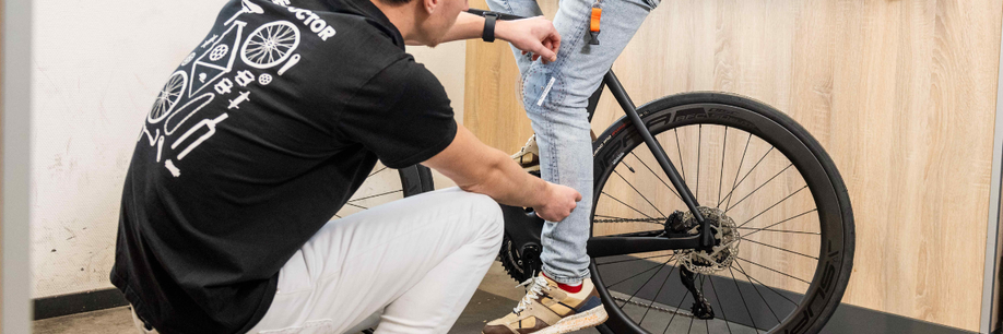 Persoon met Bike Doctor shirt met de hoek van de knie bij persoon die op racefiets zit