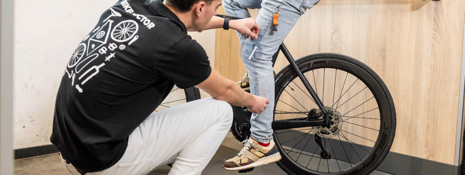 Persoon met Bike Doctor shirt met de hoek van de knie bij persoon die op racefiets zit