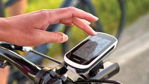 Garmin Edge Explore 2 op fiets met Garmin Varia voorlicht eronder en persoon die touchscreen gebruikt