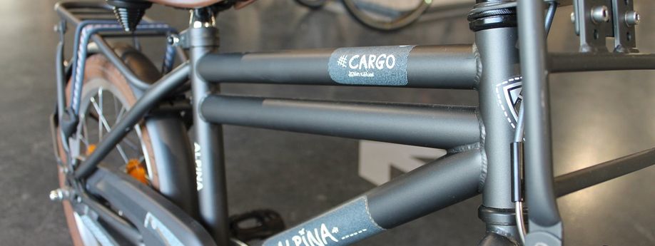 Groene Alpina Cargo kinderfiets met bruin zadel en bruine banden in de showroom van 12GO Biking