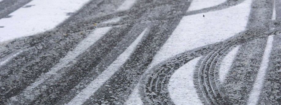 Bandensporen van auto's op een asfaltweg met sneeuw