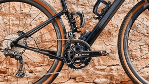 Zwarte gravelbike met bruine skinwall banden en een Shimano GRX820 afmontage voor een bruingesteente muur