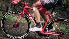 Rode Trek racefiets en steeksassen met profrenner en nummer 206 op de fiets over afsaltweg de berg op