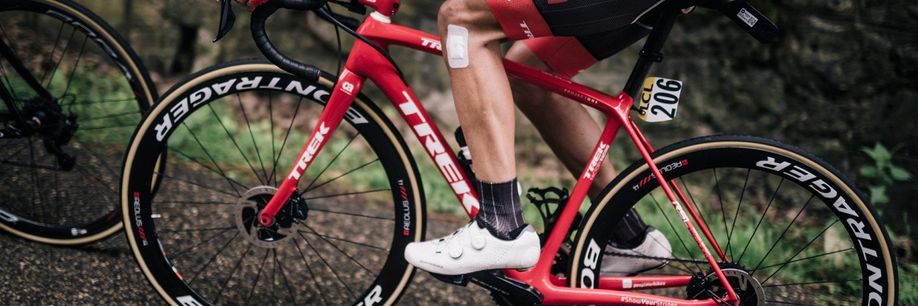Rode Trek racefiets en steeksassen met profrenner en nummer 206 op de fiets over afsaltweg de berg op