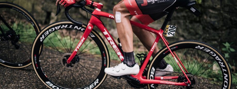 Rode Trek racefiets en steeksassen met profrenner en nummer 206 op de fiets over afsaltweg de berg op