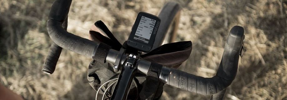 Wahoo ELEMNT Roam op fiets gemonteerd met tas eronder op gras ondergrond