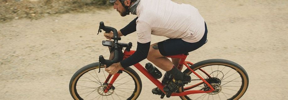 Rode racefiets op onverhard gravelpad met gemonteerde Wahoo ELEMNT Roam